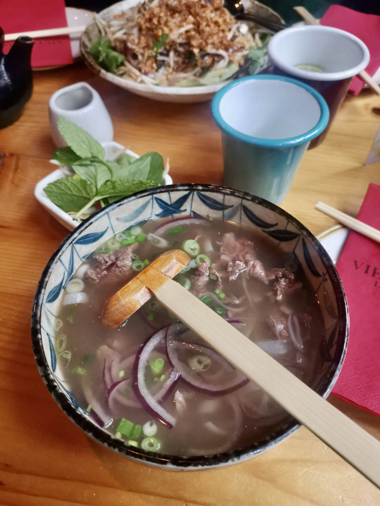 A bowl of pho sitting on a table in a restaurant in chinatown london