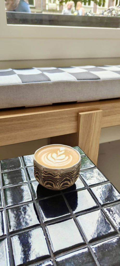 A cup of flat white sitting on a table with black tiles