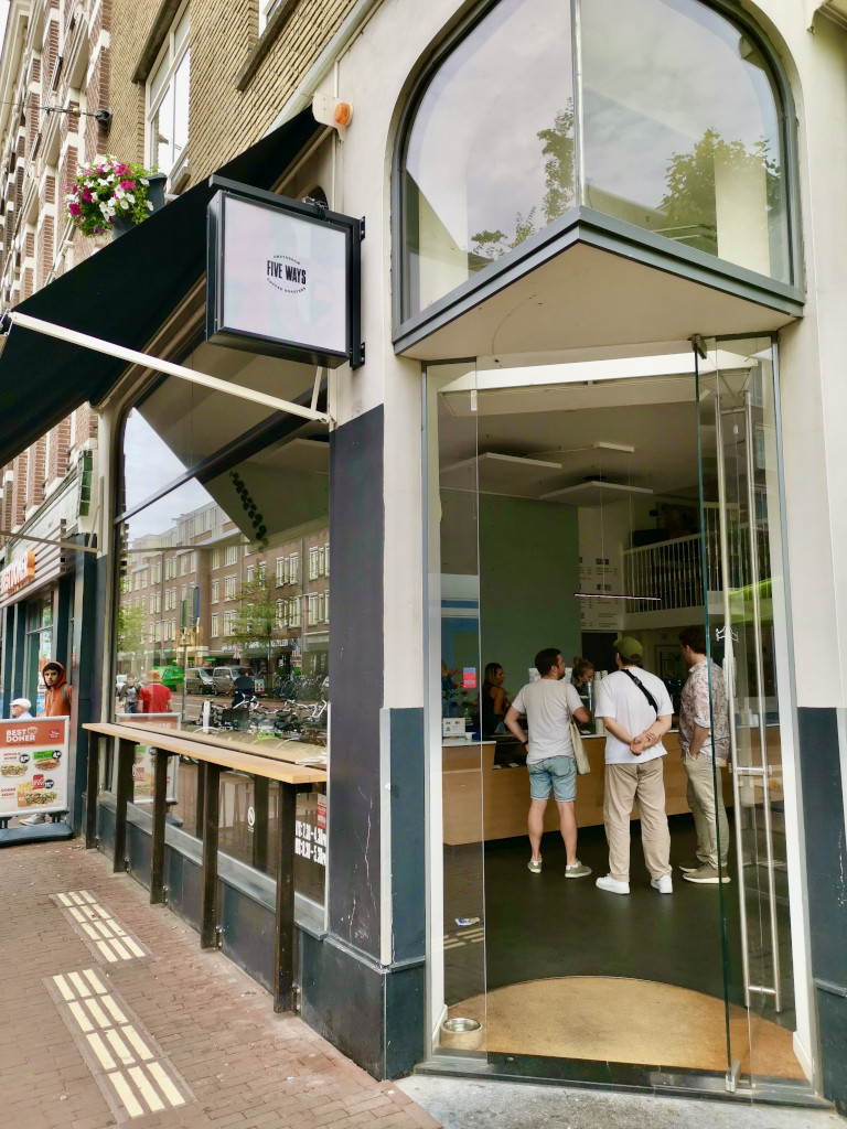 The entrance to five ways cafe with a group of people waiting in line at the counter