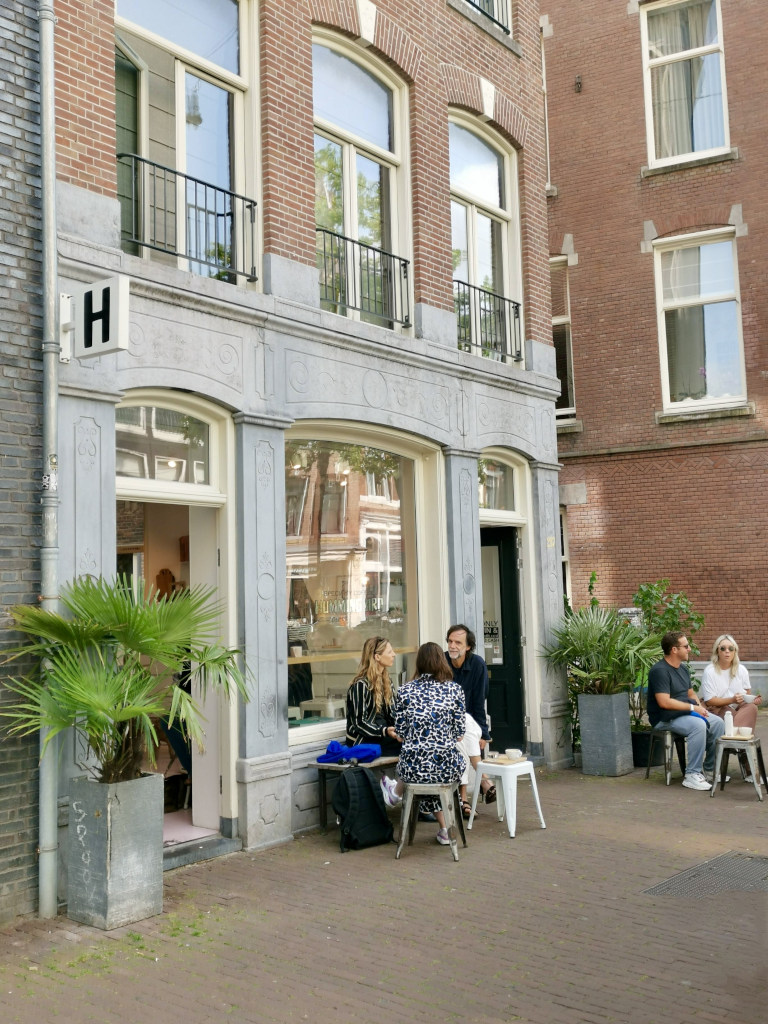 People sitting down at small tables on the street outside of a cafe