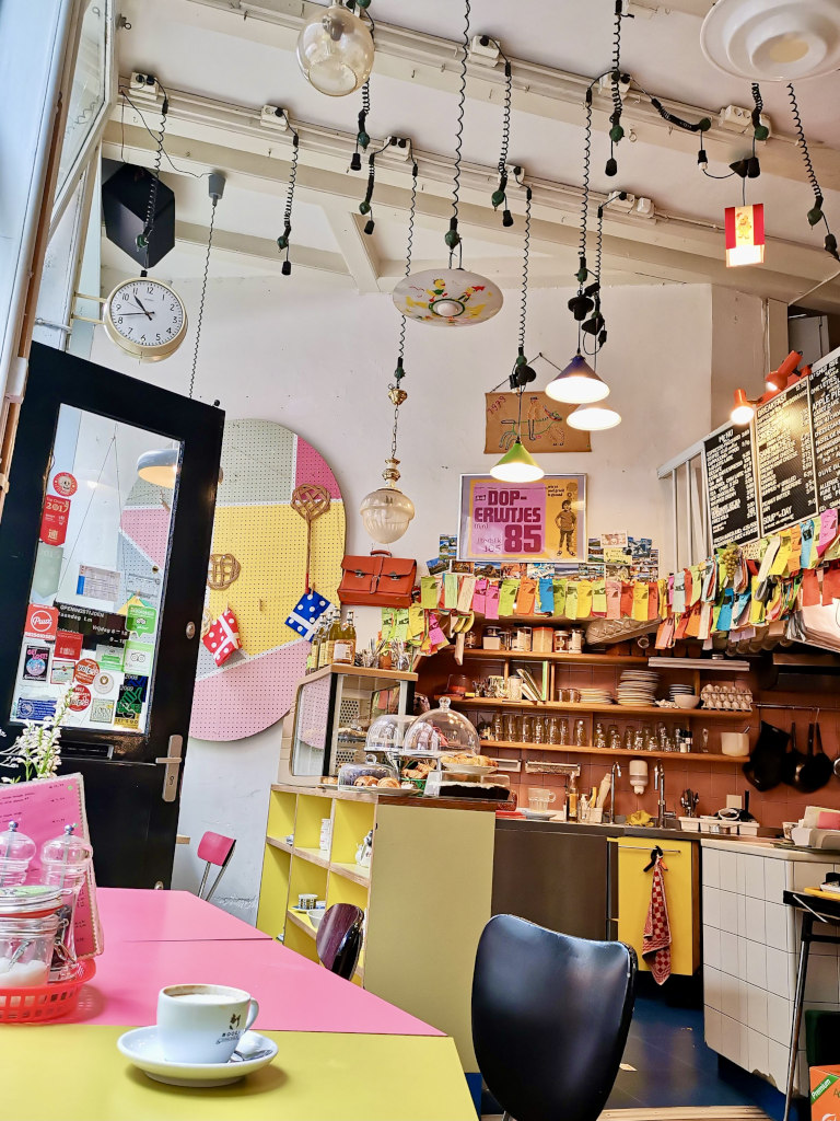 A cup of coffee sitting on a table at a colorful cafe in amsterdam