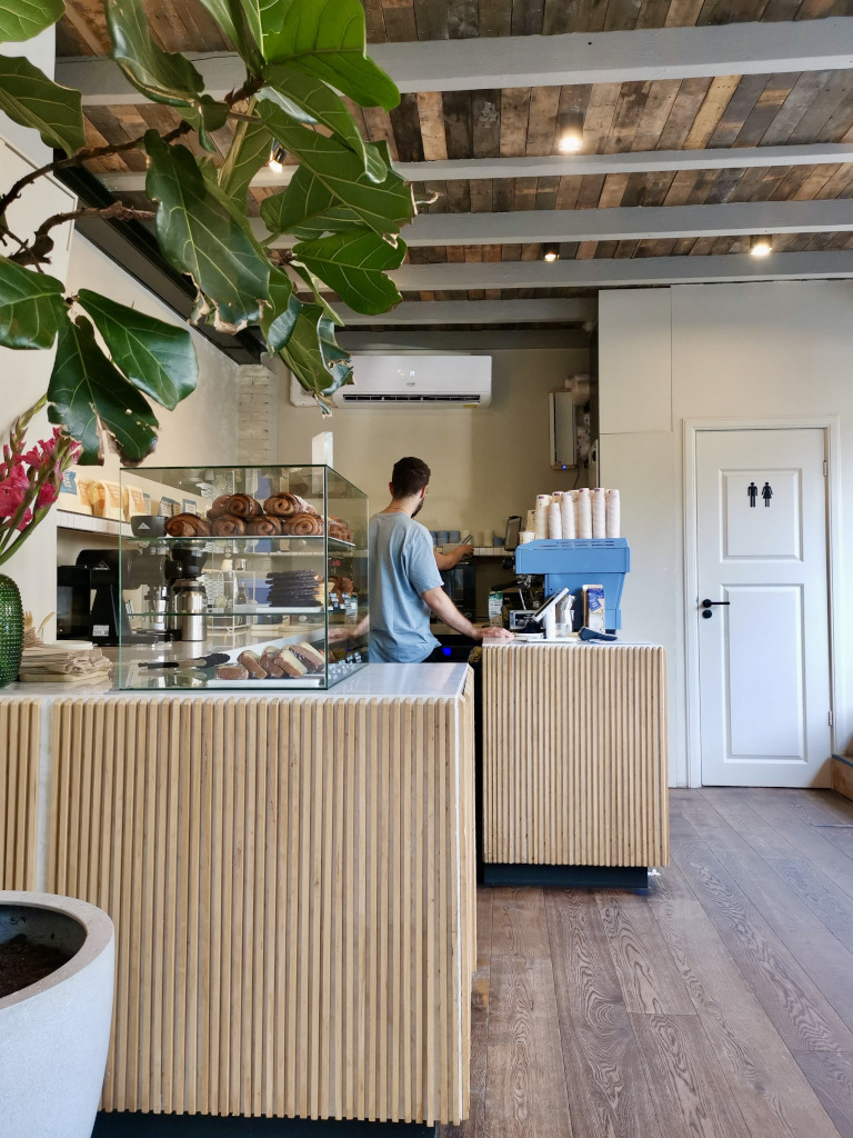 A man working at a cafe with a glass cabinet next to him full of pastries