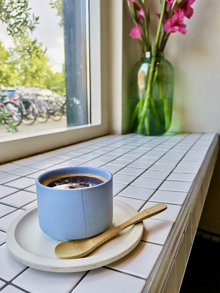 A cup of coffee sitting on a bench in luuks coffee one of the best cafes in amsterdam