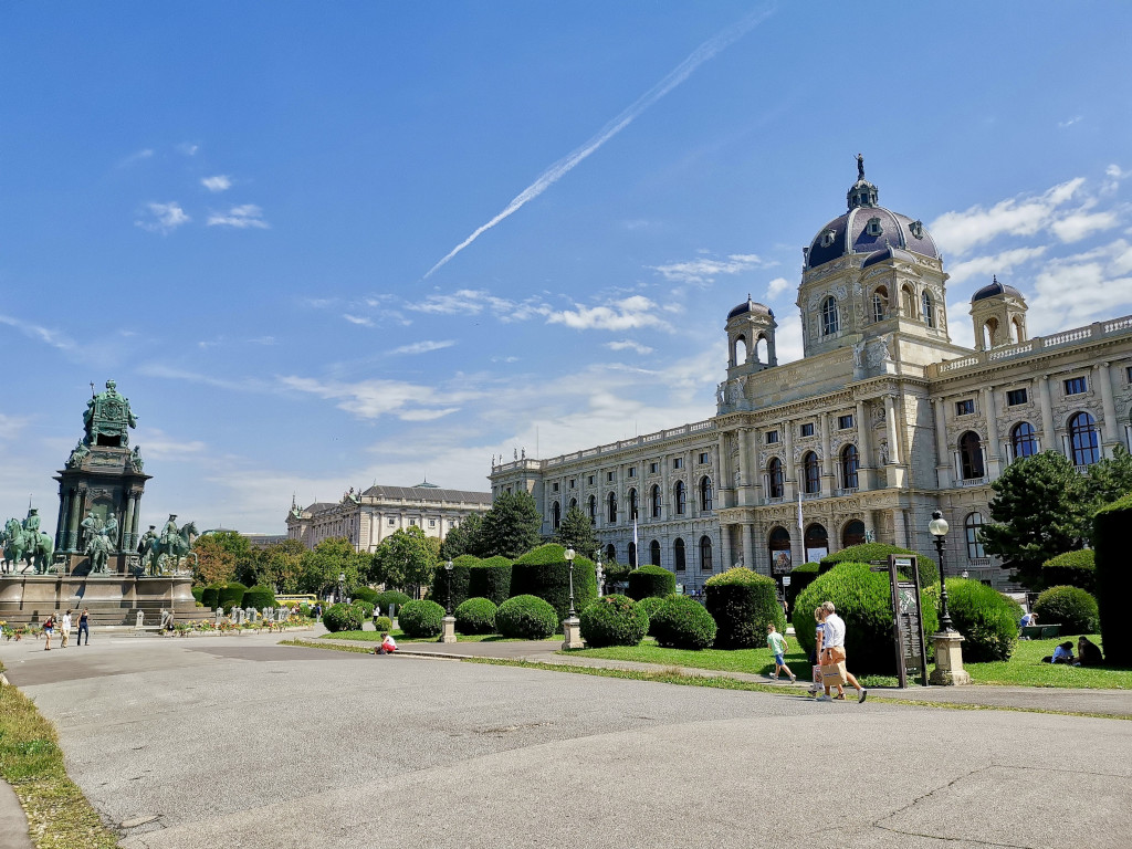 people walking in a park next to a museum in the museums quarter in vienna