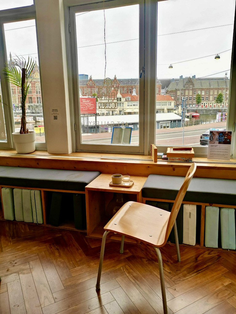 A chair sitting in front of a window next to a cup of coffee at a cafe