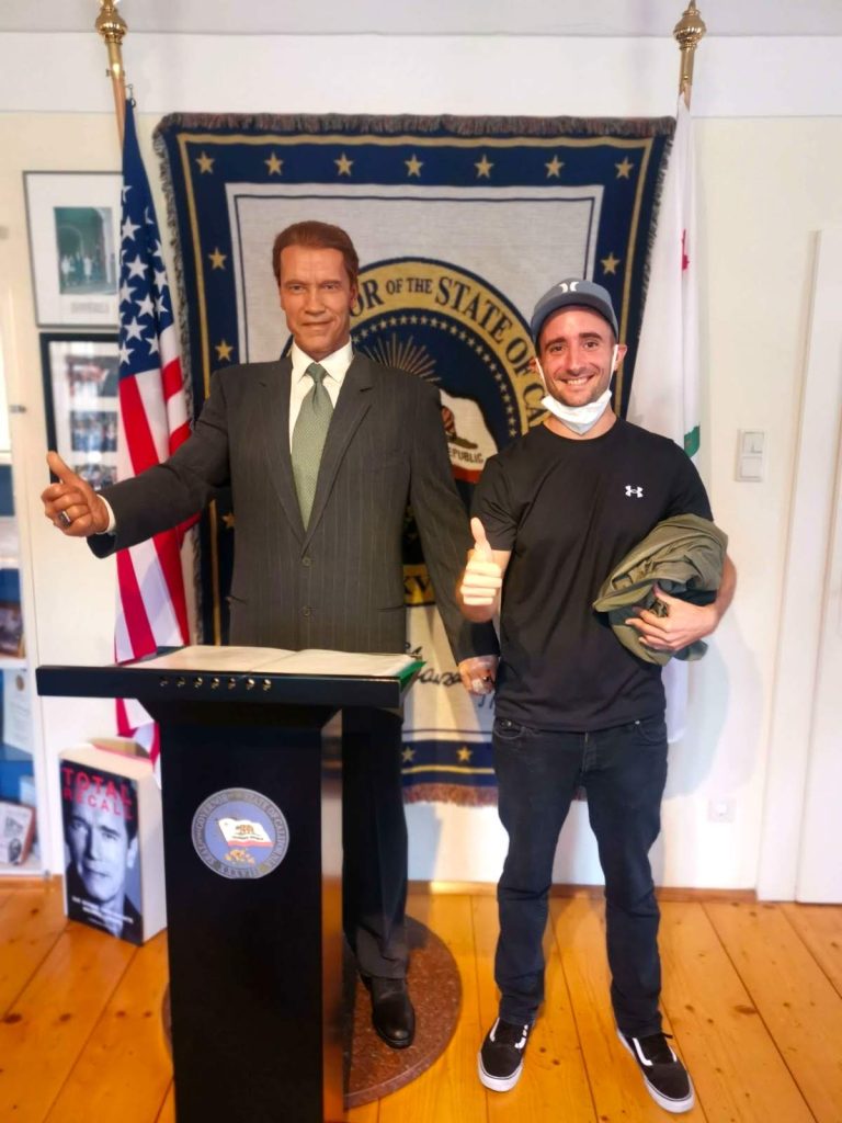 Allan standing beside a wax statue of Arnold Schwarzenegger at the museum.