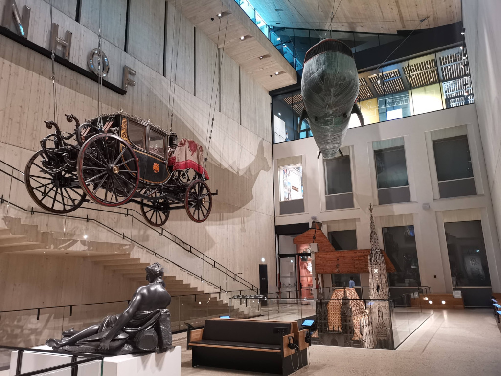 The interior of the wien museum karsplarz with an old cart and a model of a whale hanging from the ceiling