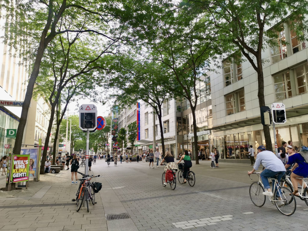 People riding bikes and walking down the street in one of the main shopping streets in Vienna