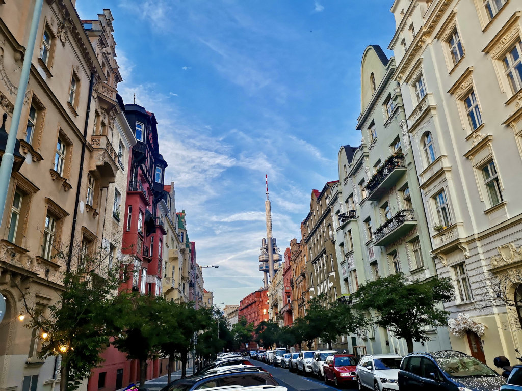 A street in vinohrady prague with a communications tower in the background