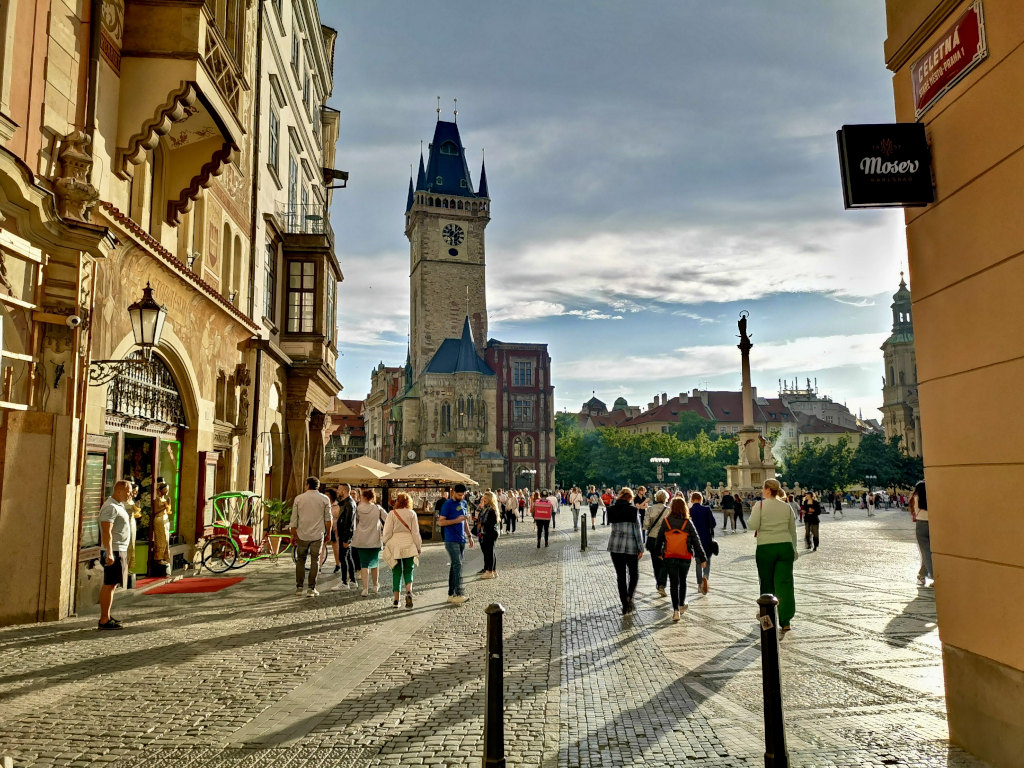 People walking on the prague main square close to sunset during a prague itinerary