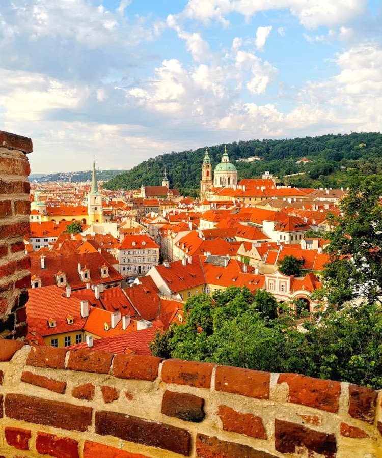 A panoramic view over Prague's Malá Strana framed by the red brick walls of Prague Castle, a must-visit on a 2-Day Prague itinerary.