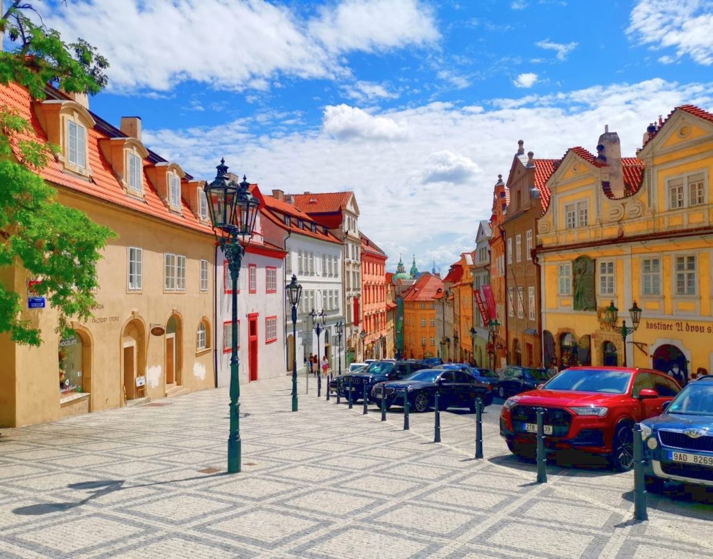 A fairly steep cobblestone street with colorful classical styled buildings leading up to Prague Castle. 