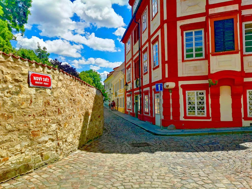 A bright red and yellow building on the cobblestone street of Nový Svět near Prague Castle.