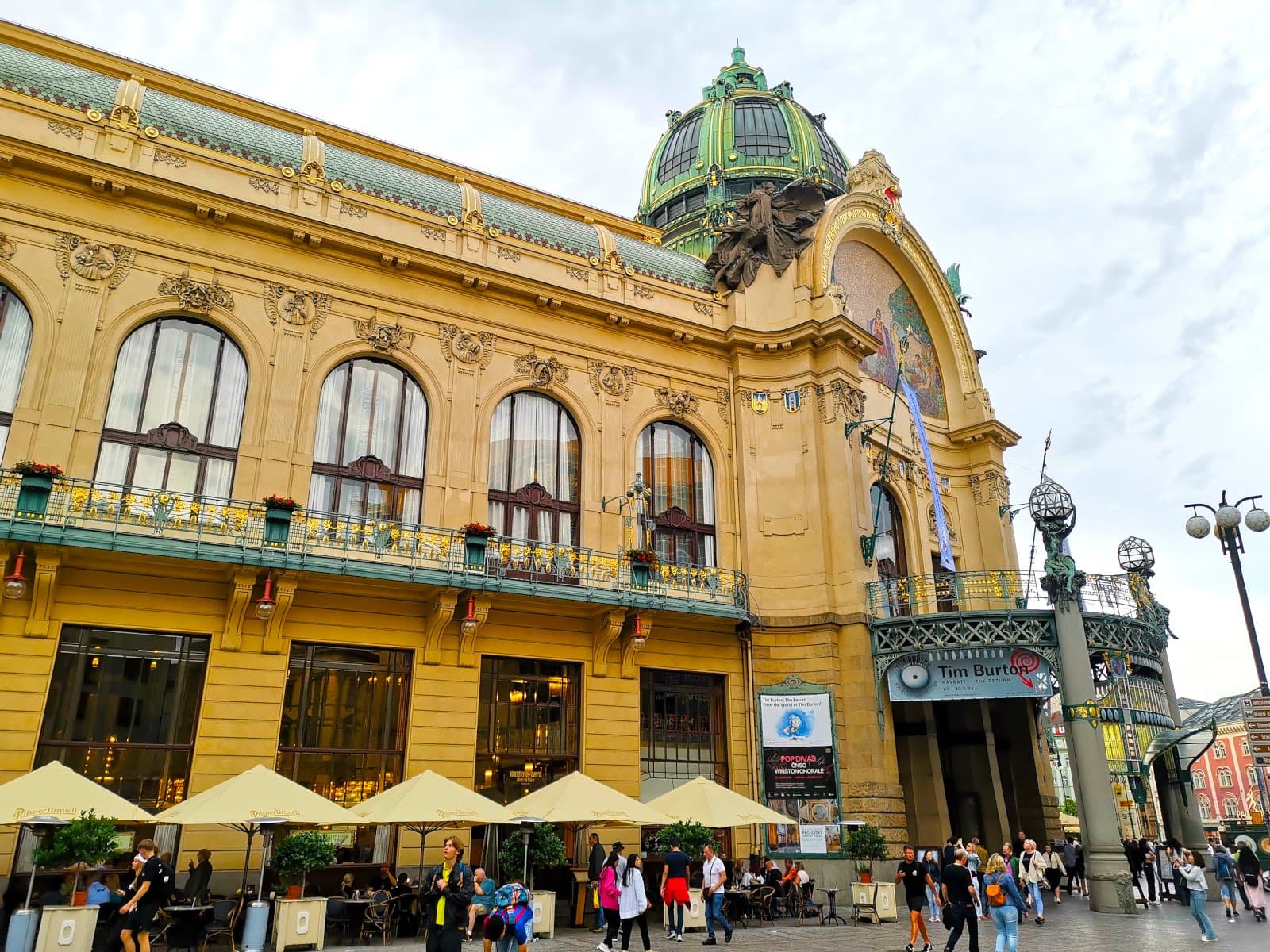 Exterior of Obecní Dům Concert Hall in Prague with a yellow Art Nouveau facade with big windows and a grand entrance.