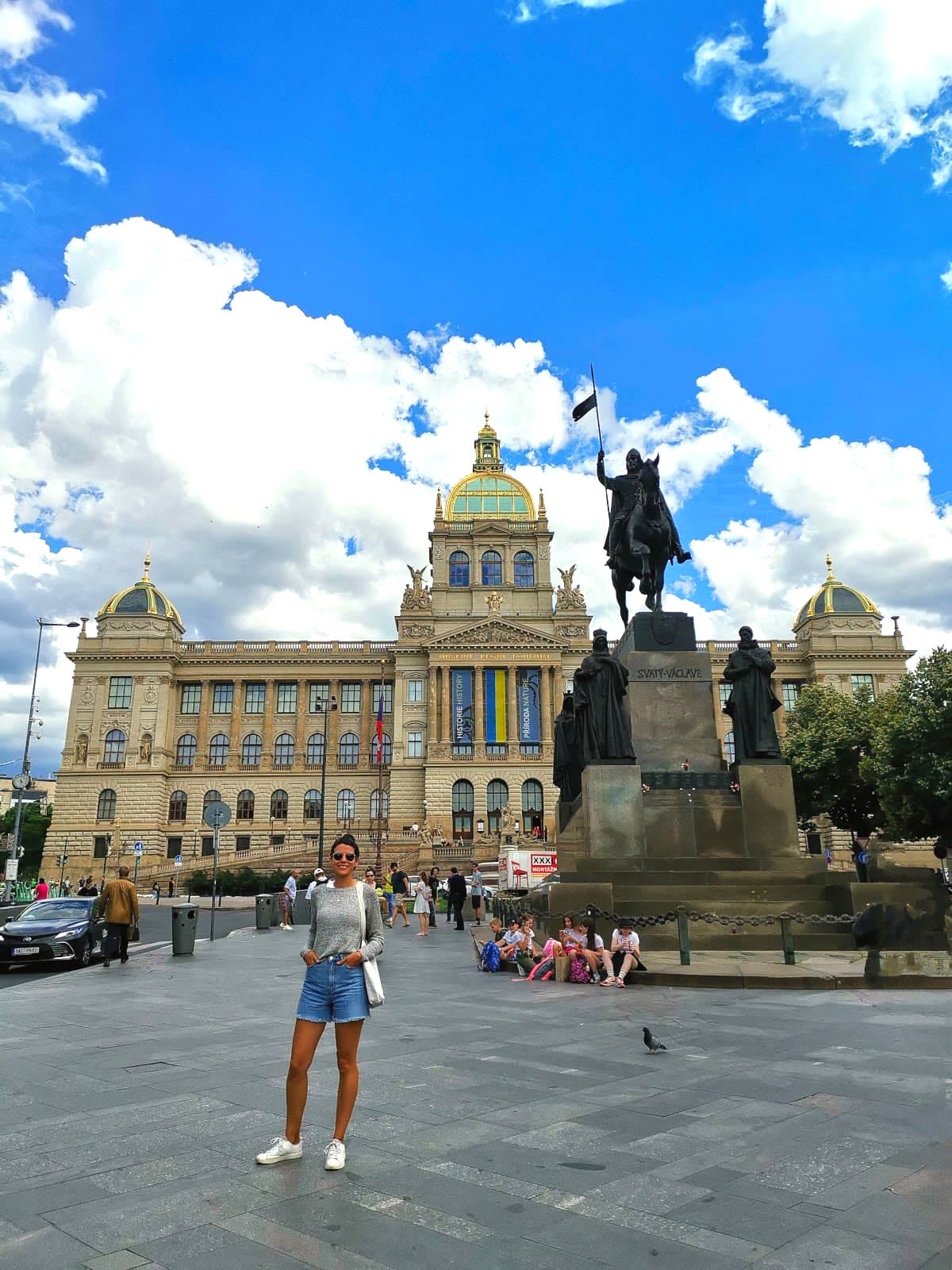 Katharina standing in front of the National Museum, next to the Statue of Saint Wenceslas, a man sitting on a horse holding up a flag.