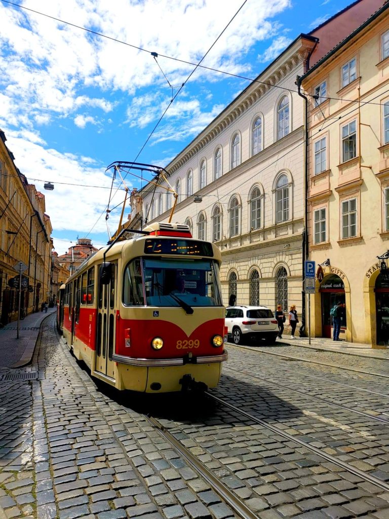 An old red tram going down the street in Malá Strana in Prague, Czech Republic.