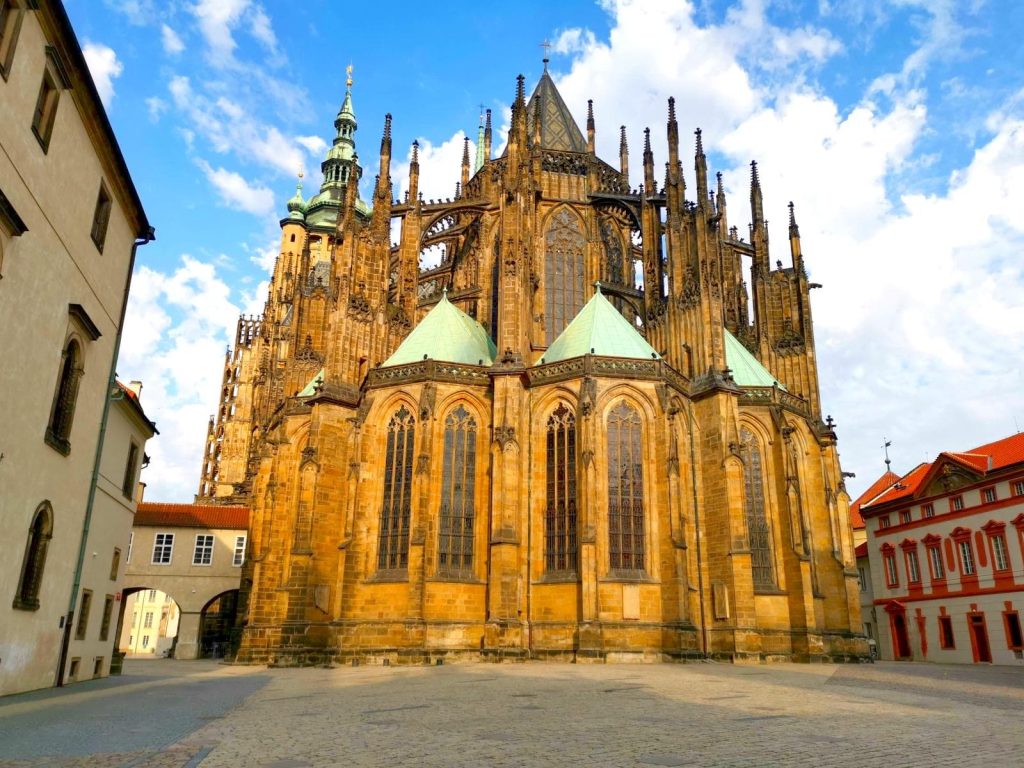 Back front of St. Vitus Cathedral at Prague Castle with lots of small towers, light green roofs and high narrow windows.