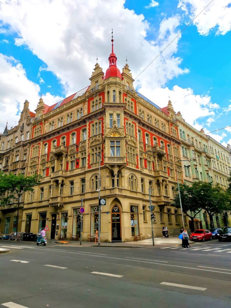 Beautiful 5-story Art Nouveau corner building in Vinohrady with red-painted walls, window decorations, and small decorative towers.