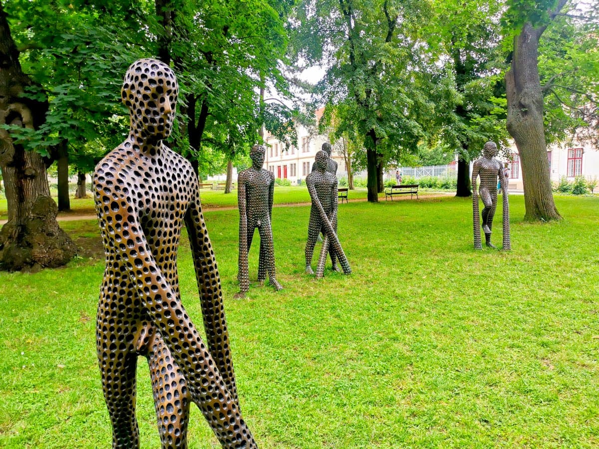 A group of statues in form of humans with lots of holes in them in  a park next to the Vyšehrad fortress.