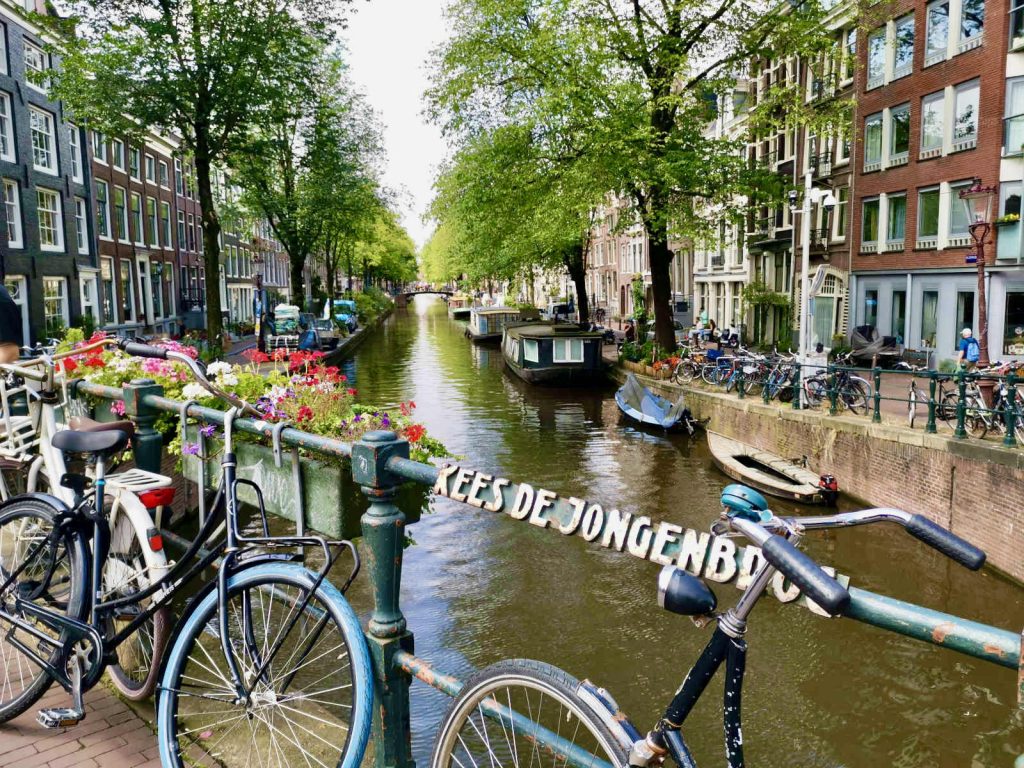 Bikes leaning on a railing next to a canal in amsterdam