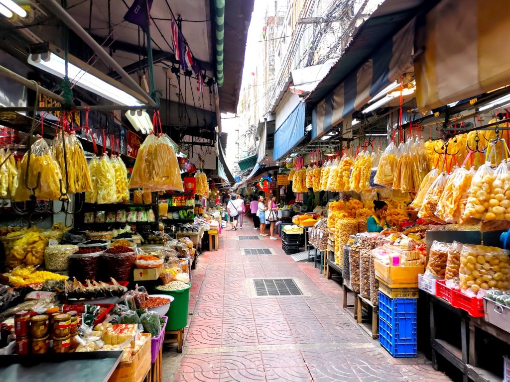 An alley in a market in Chinatown, Bangkok with a range of interesting dried yellow food products in plastic bags for sale.