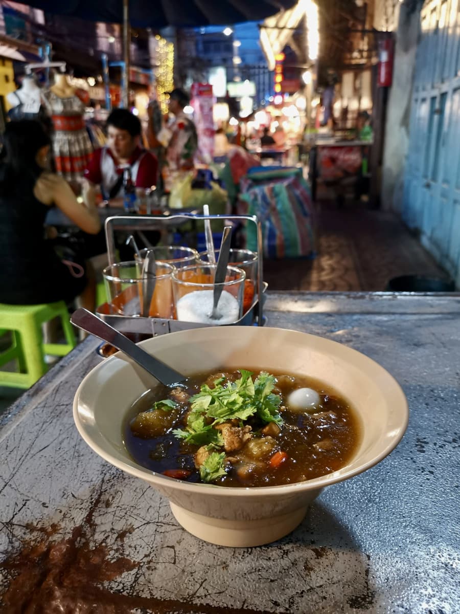 A bowl of brown thick fish maw soup on a metal table in Bangkok's Chinatown.