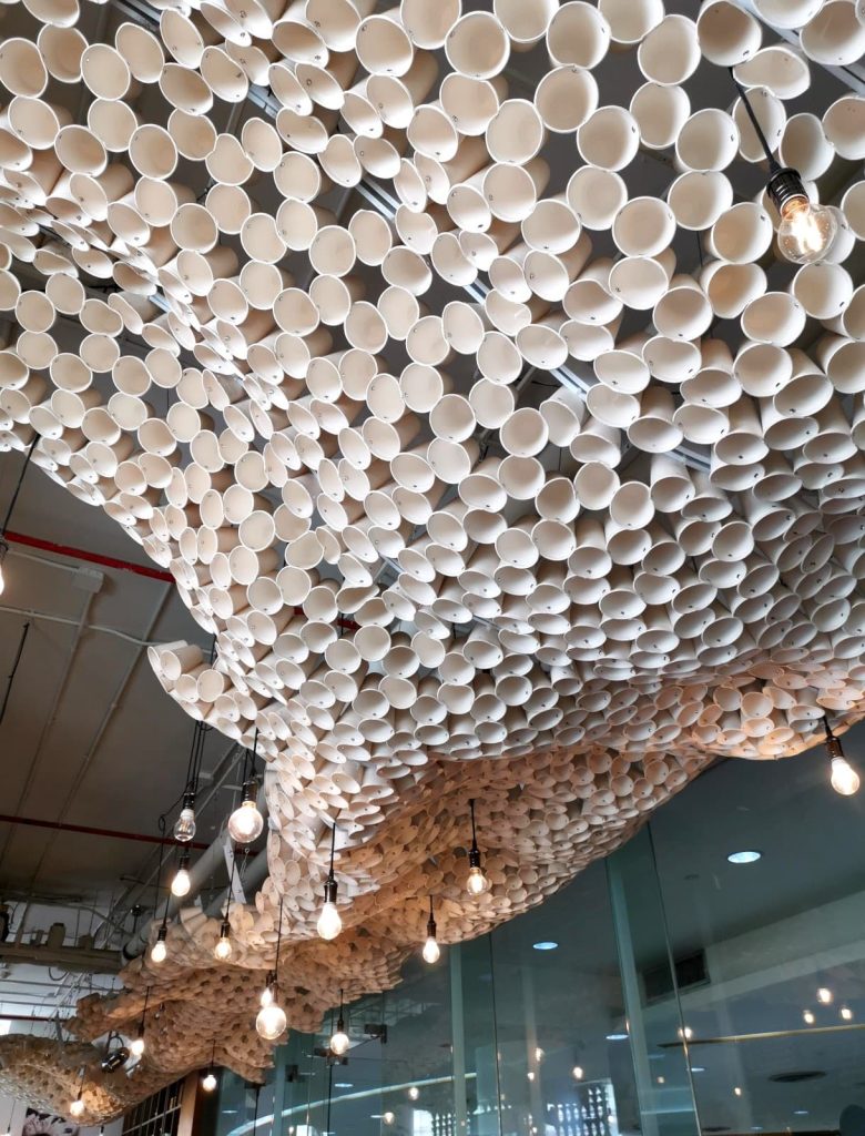 Wave of paper cups hanging from the ceiling as art decoration in the cafe.