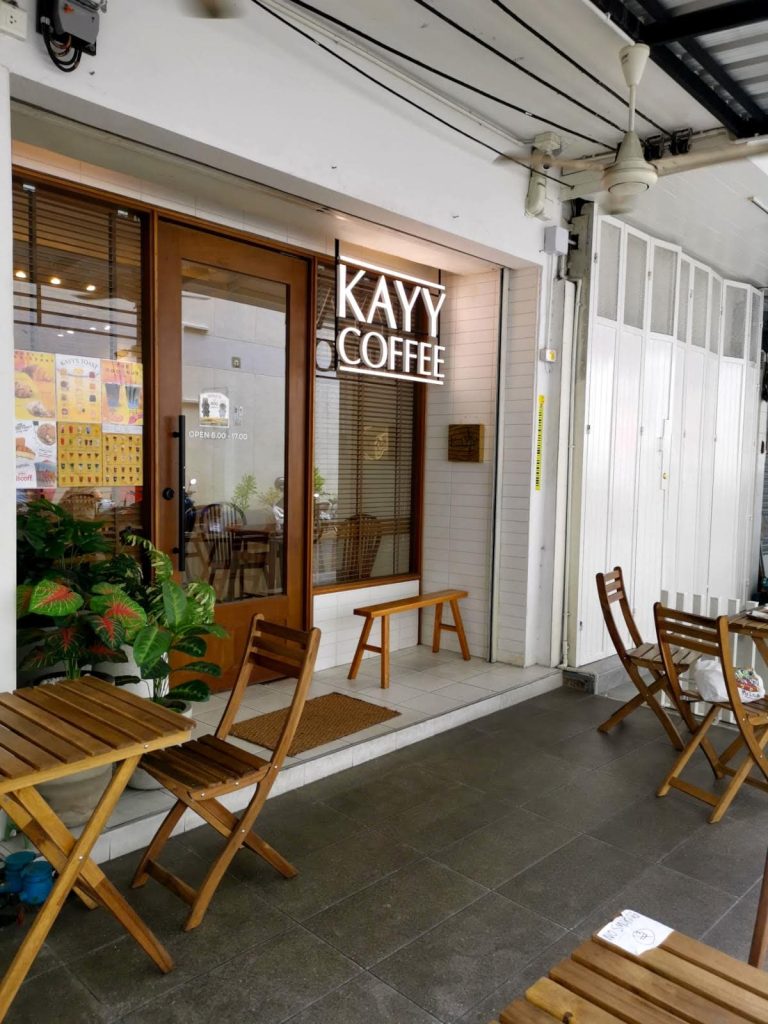 Wooden door entrance of Kayy Coffee Shop with outdoor seating.