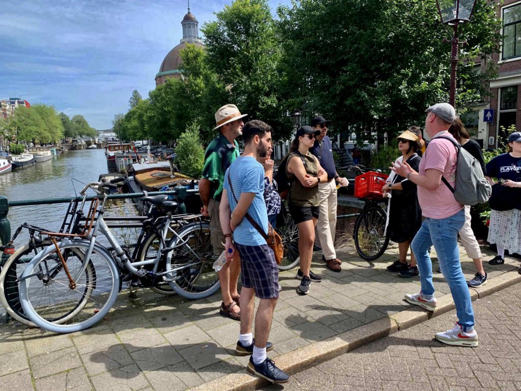 A group of people listening to a walking tour guide during an amsterdam itinerary