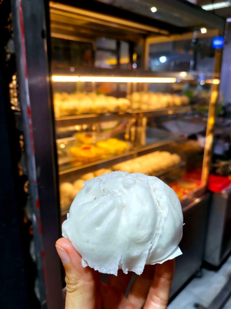 Katharina holding up a white steam bun, one of the best Chinatown Bangkok street food to sample.