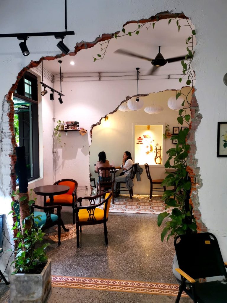 The Instagrammable seating ara of Son Cafe with white brick walls, colorful chairs and plants.