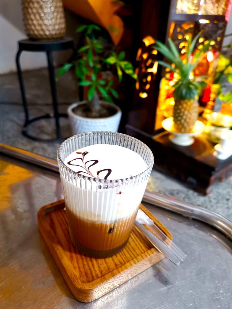 Vietnamese salt coffee on a wooden tray with a white creamy froth on top on a table at Son Cafe, a very local Hoi An cafe.