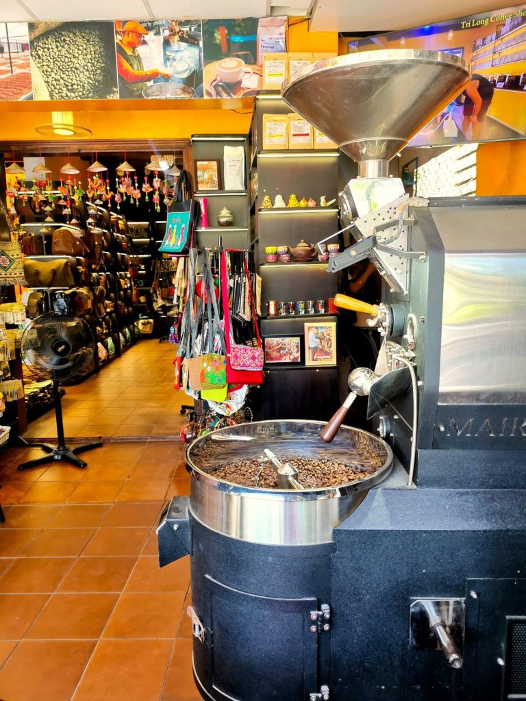 A roaster with coffee beans in front of Tri Long's Hoi An Coffee Shop.